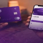 Cartão Nubank Ultravioleta sendo segurado junto com celular exibindo aplicativo financeiro